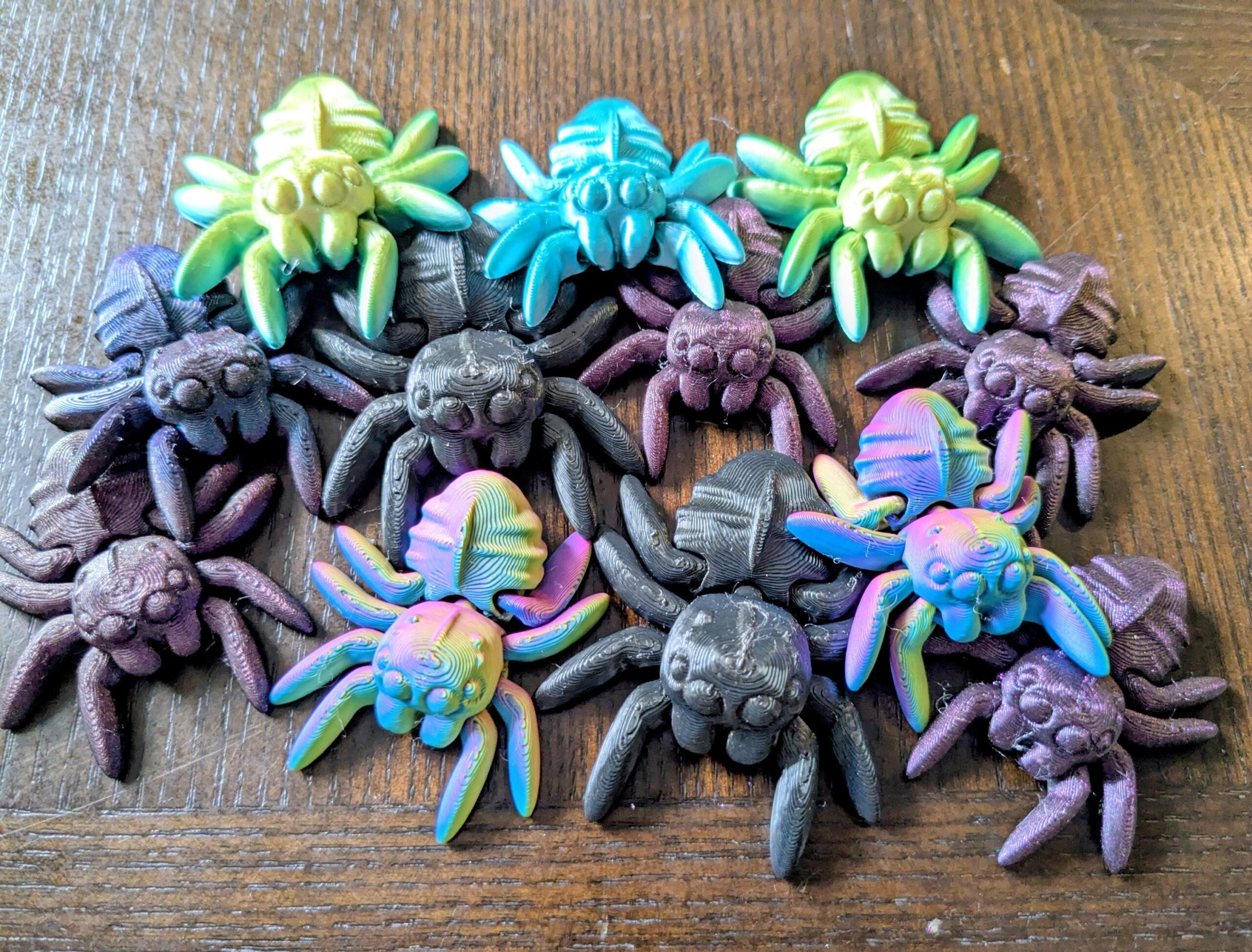 May include: A collection of colorful, 3D-printed spider figurines. The spiders are in various colors, including green, blue, purple, and rainbow hues. Each spider has eight legs and a detailed body, perfect for Halloween decor or a unique gift.