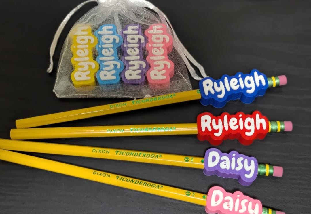 May include: Four yellow Dixon Ticonderoga pencils with custom name erasers in blue, red, purple, and pink. The erasers feature the names Ryleigh and Daisy in white text. A sheer white drawstring bag contains four additional name erasers.