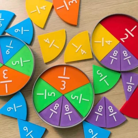 May include: A set of colorful plastic fraction circles and segments in red, orange, yellow, green, blue, and purple. Each piece features a raised white fraction number, including 1/2, 1/3, 1/4, 1/5, 1/6, and 1/8, designed for educational math learning.